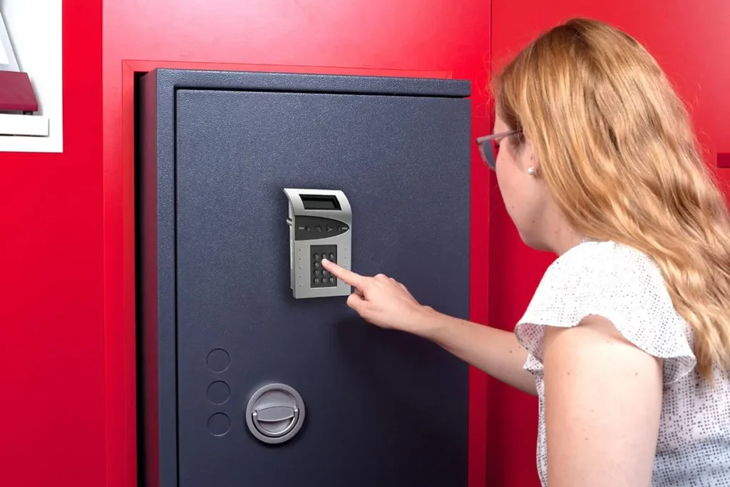 Personne entrant un code sur un coffre-fort électronique pour changer le code d’un coffre fort